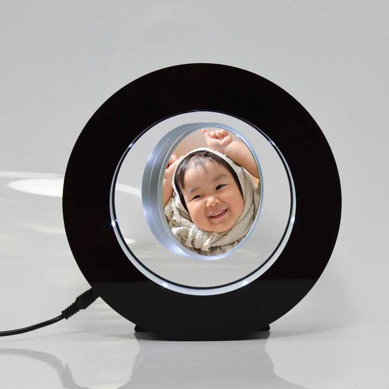 Black magnetic levitation miniature photo frame with LED lights displaying a floating photo in the center
