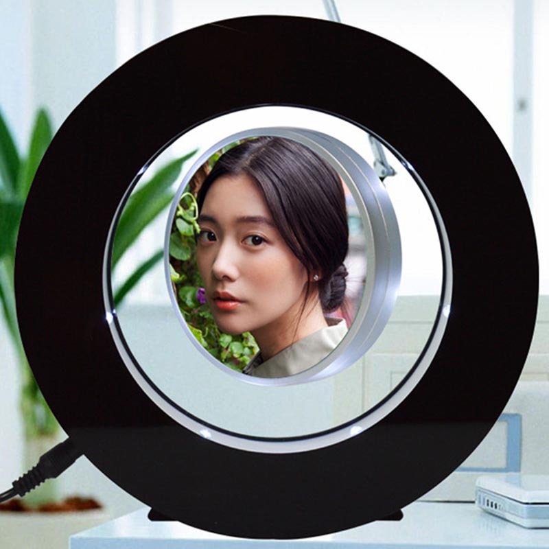 Magnetic levitation miniature photo frame with black circular design and LED lights displaying a portrait photo.