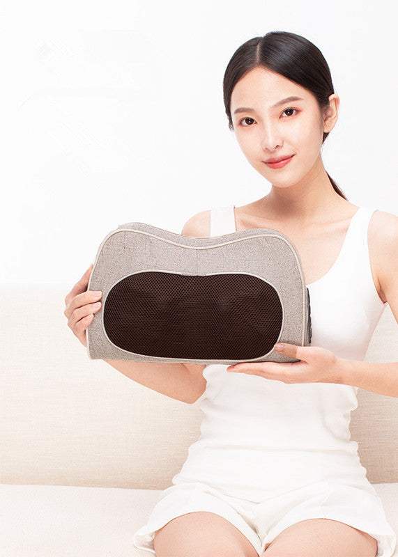 Woman holding a multifunctional cervical spine massager massage pillow with rectangular trapezoid shape and black mesh center
