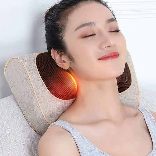 A person is seated, using a beige cervical spine massager massage pillow, which emits infrared light, against a white background.